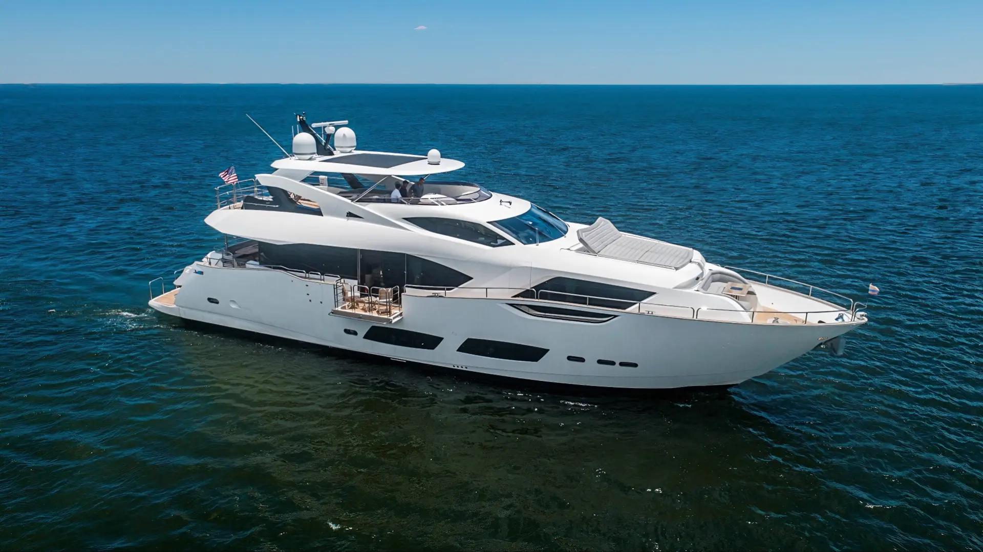 Sunseeker 95 cruising on open sea, featuring sleek modern design, sun pads on the bow, and multi-level decks.