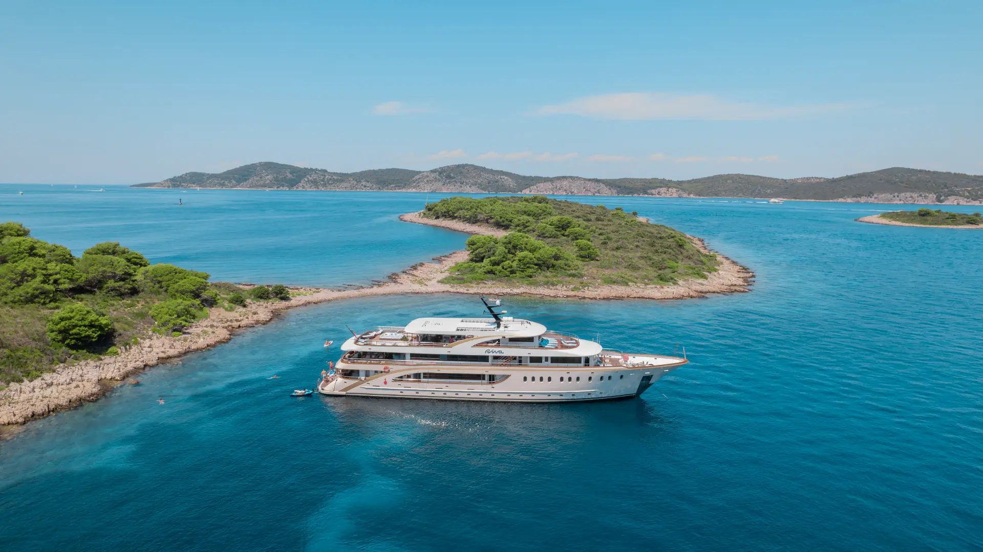 Luxury Mini Cruiser Riva floating peacefully in a turquoise bay, its white hull contrasting beautifully with the vibrant Adriatic seascape.