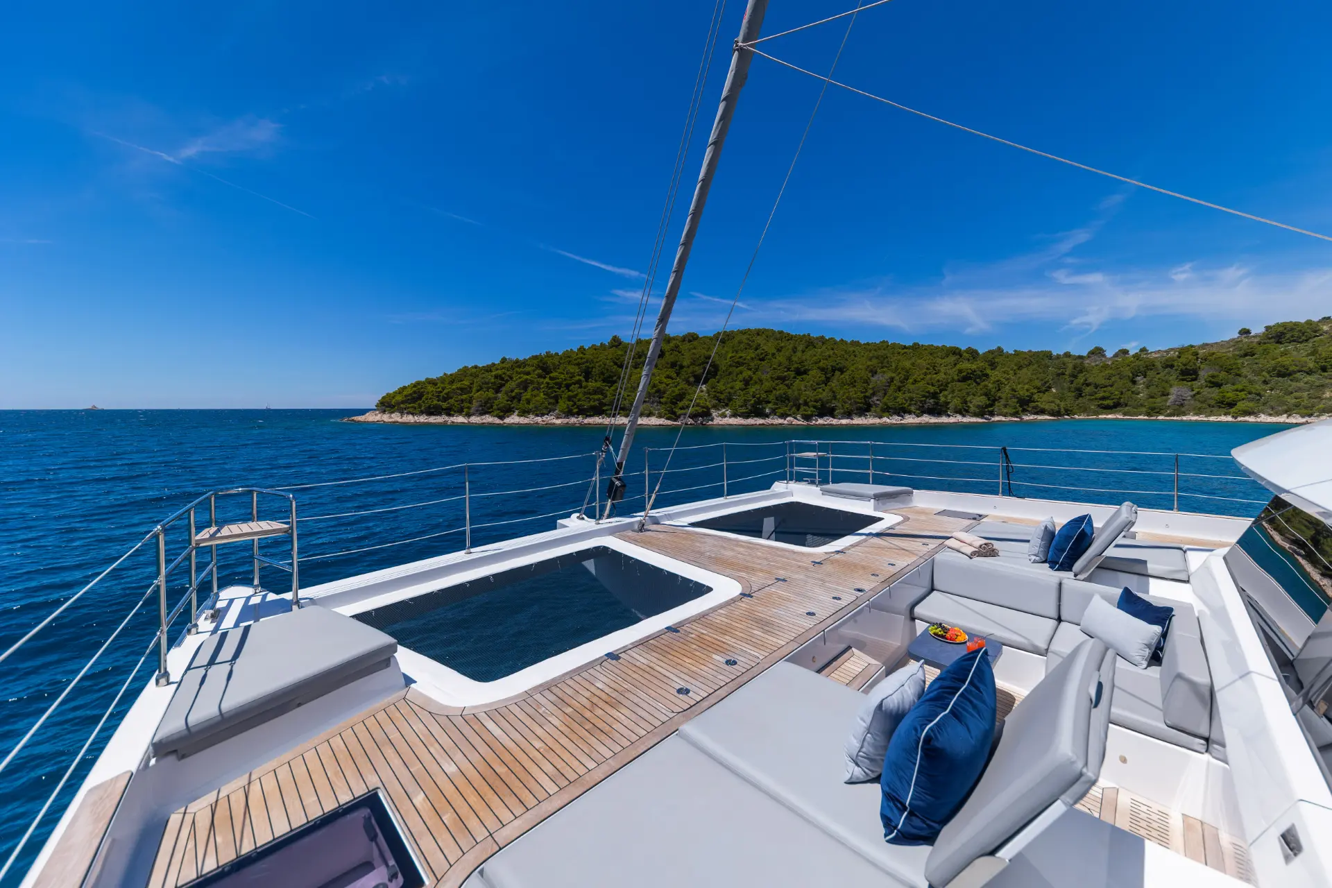 Sunreef 60 close view of foredeck in cruising, green island in distance, perfect scene for luxury sailing.