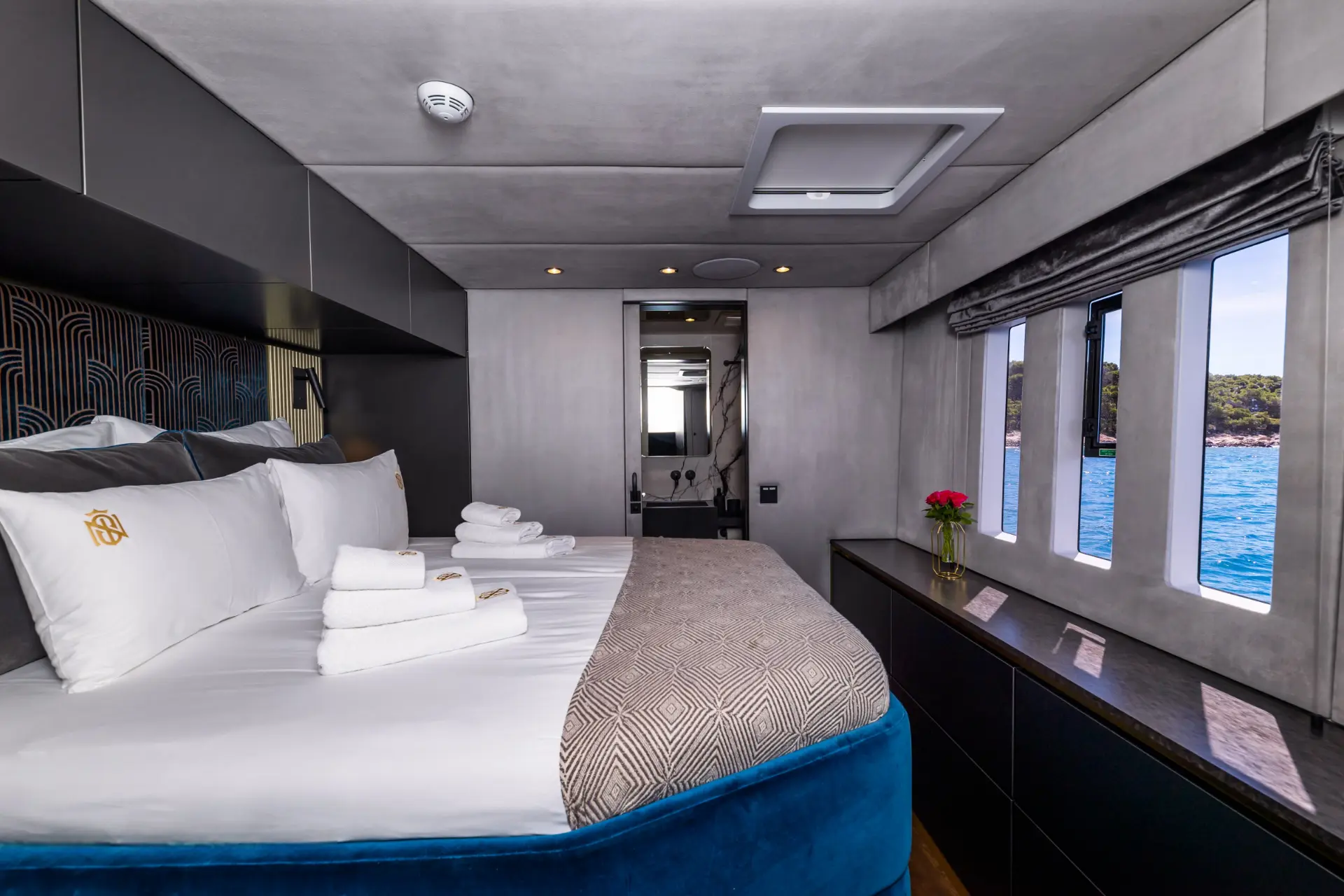 Sunreef 60 elegant cabin featuring double bed, door to bathroom, and big windows with bay view.