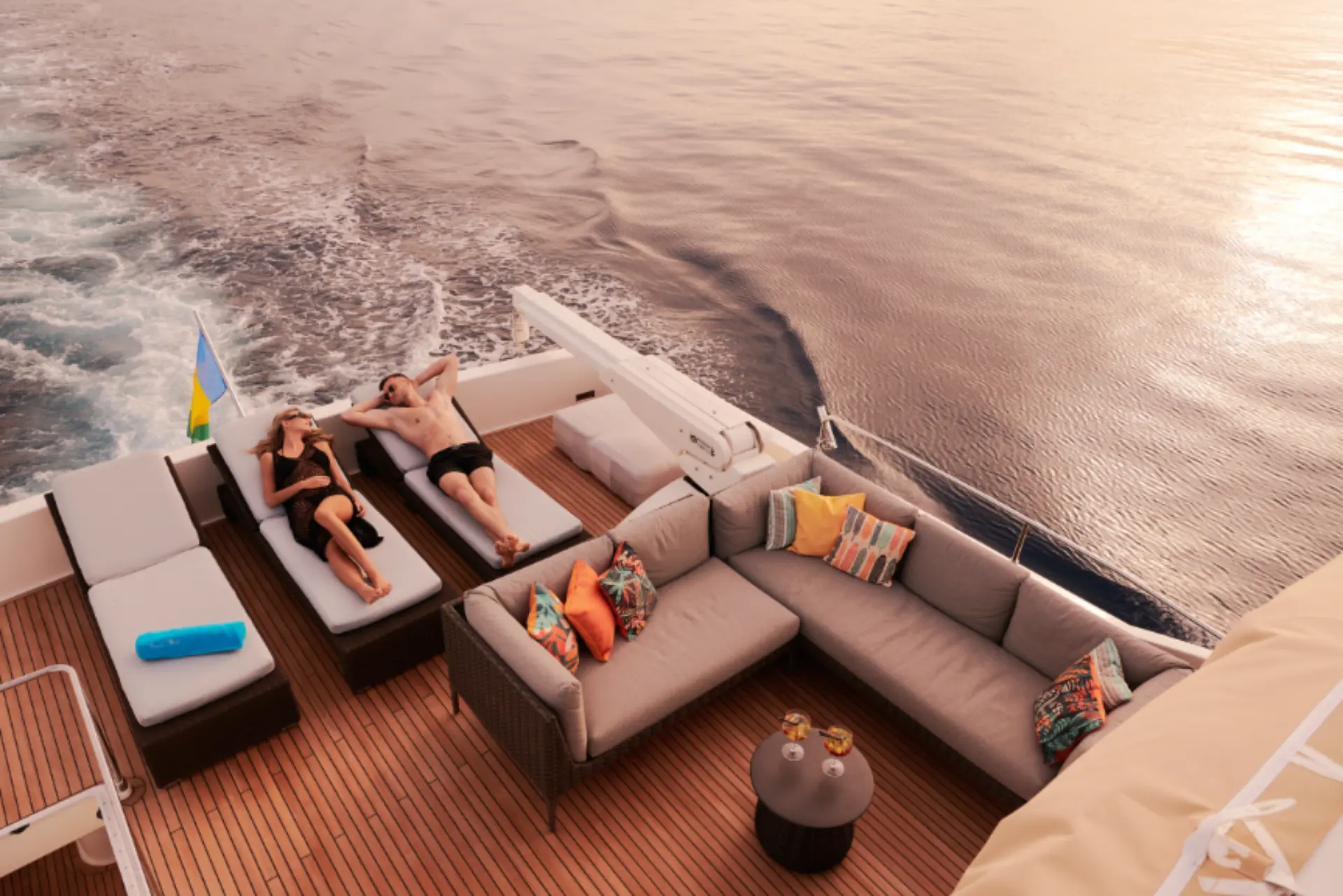 Friend’s Boat – top view of flybridge aft lounge, two guests relaxing and sunbathing in a calm bay.