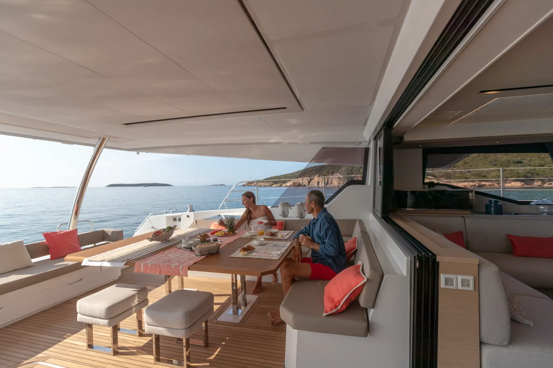FLORAMYE – side perspective of salon entrance and sliding doors, couple socializing at left aft dining area.