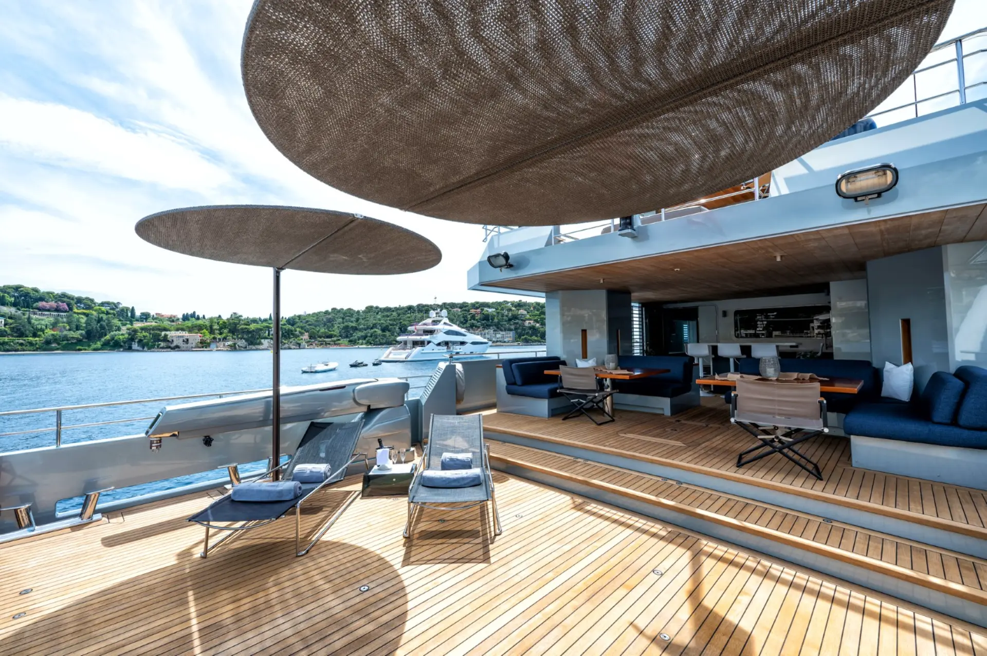 Caladan – aft deck featuring sunbeds with umbrellas, large shaded lounge and dining area, yacht entrance.