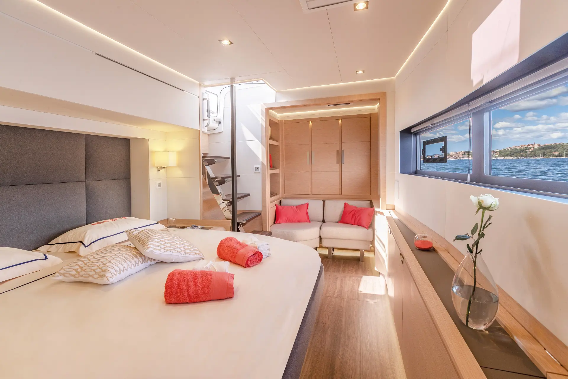 Master cabin featuring light brown and orange tones, double bed upfront, sofa behind, ladders on left side.