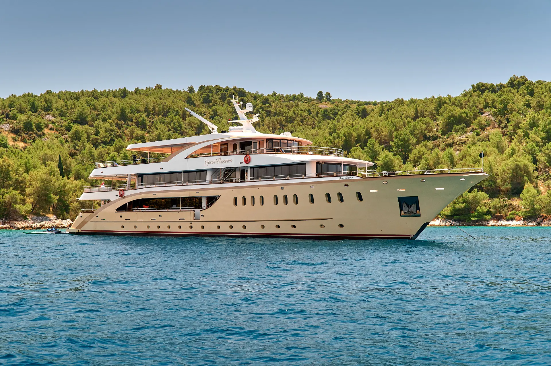 Luxury mini cruiser Queen Eleganza - anchored front side view in a calm bay surrounded by lush green hills