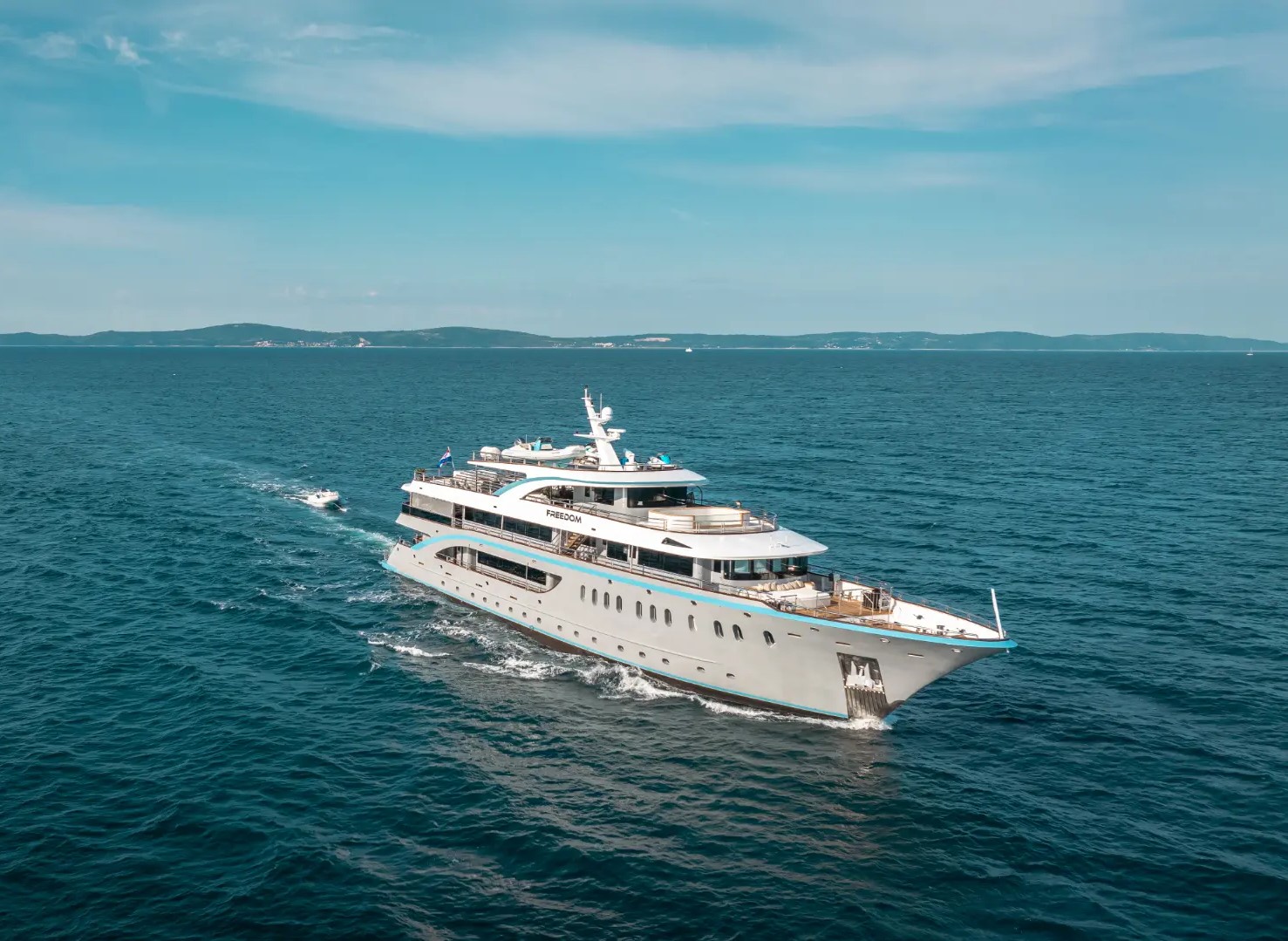 Luxury mini cruiser Freedom – cruising with front side view, lush green islands in the background