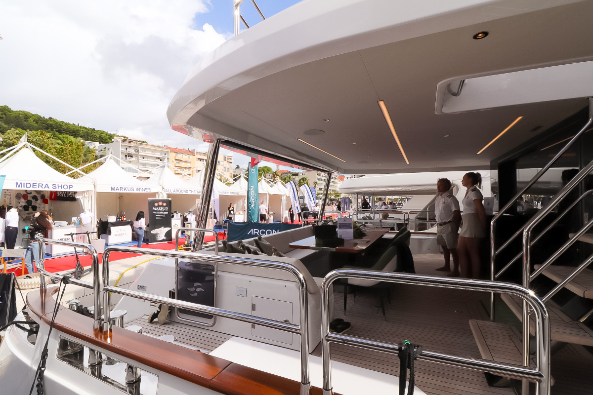 Majera – on the pier, shaded aft with table setup, crew onboard, yacht show around.