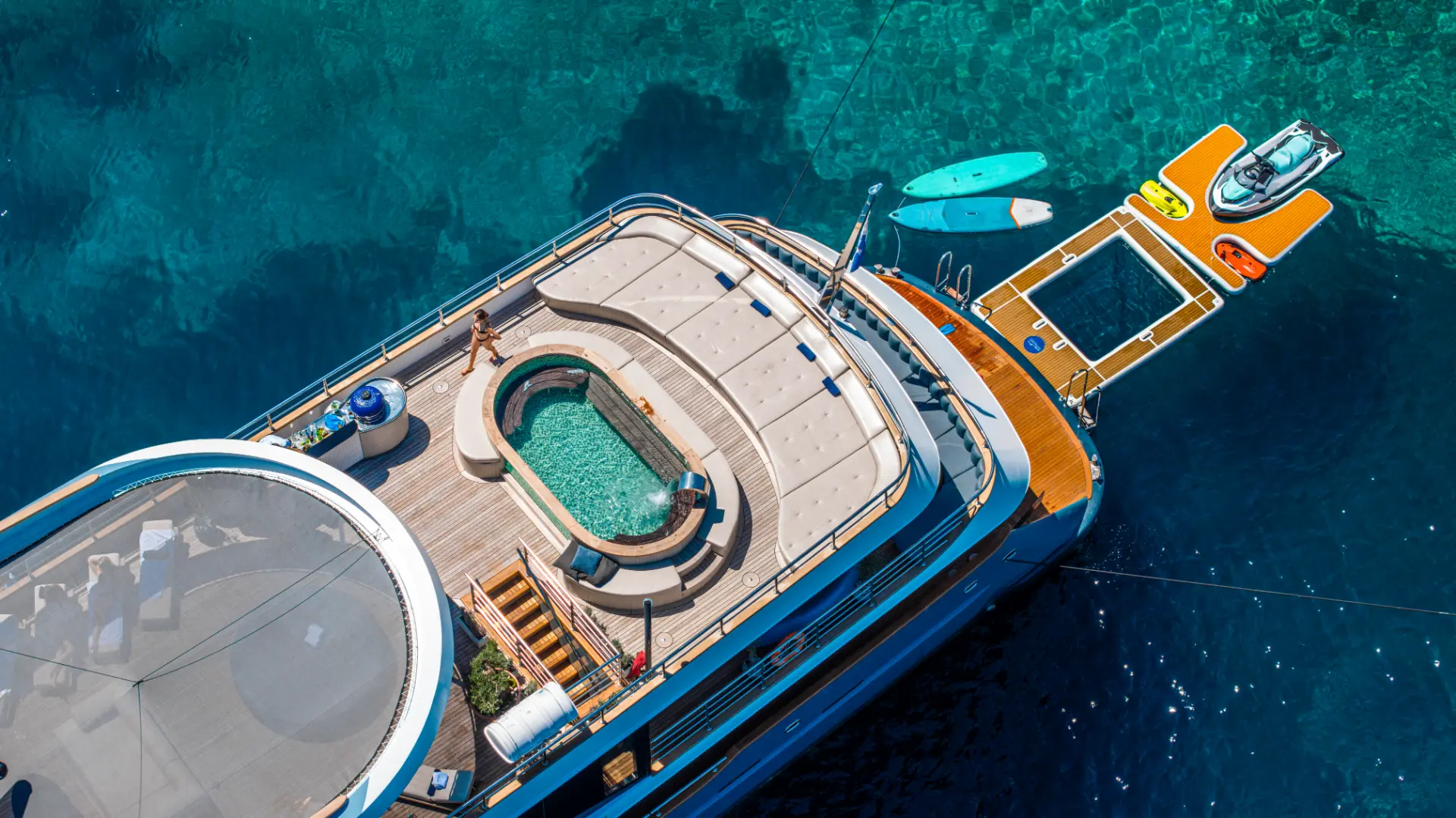 Bella – Close aerial aft view of sundeck with pool and swim platform equipped with exciting water toys.