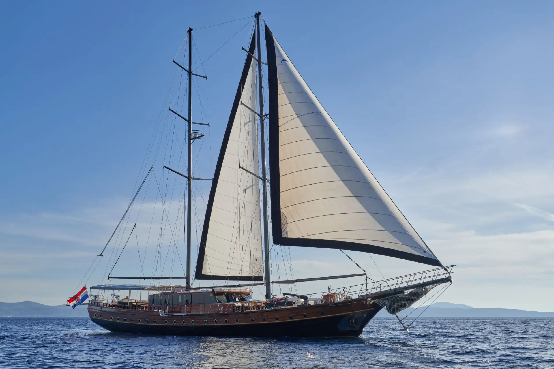 Stella Maris – side view, sails up under clear skies, showcasing her classic gulet-style elegance.