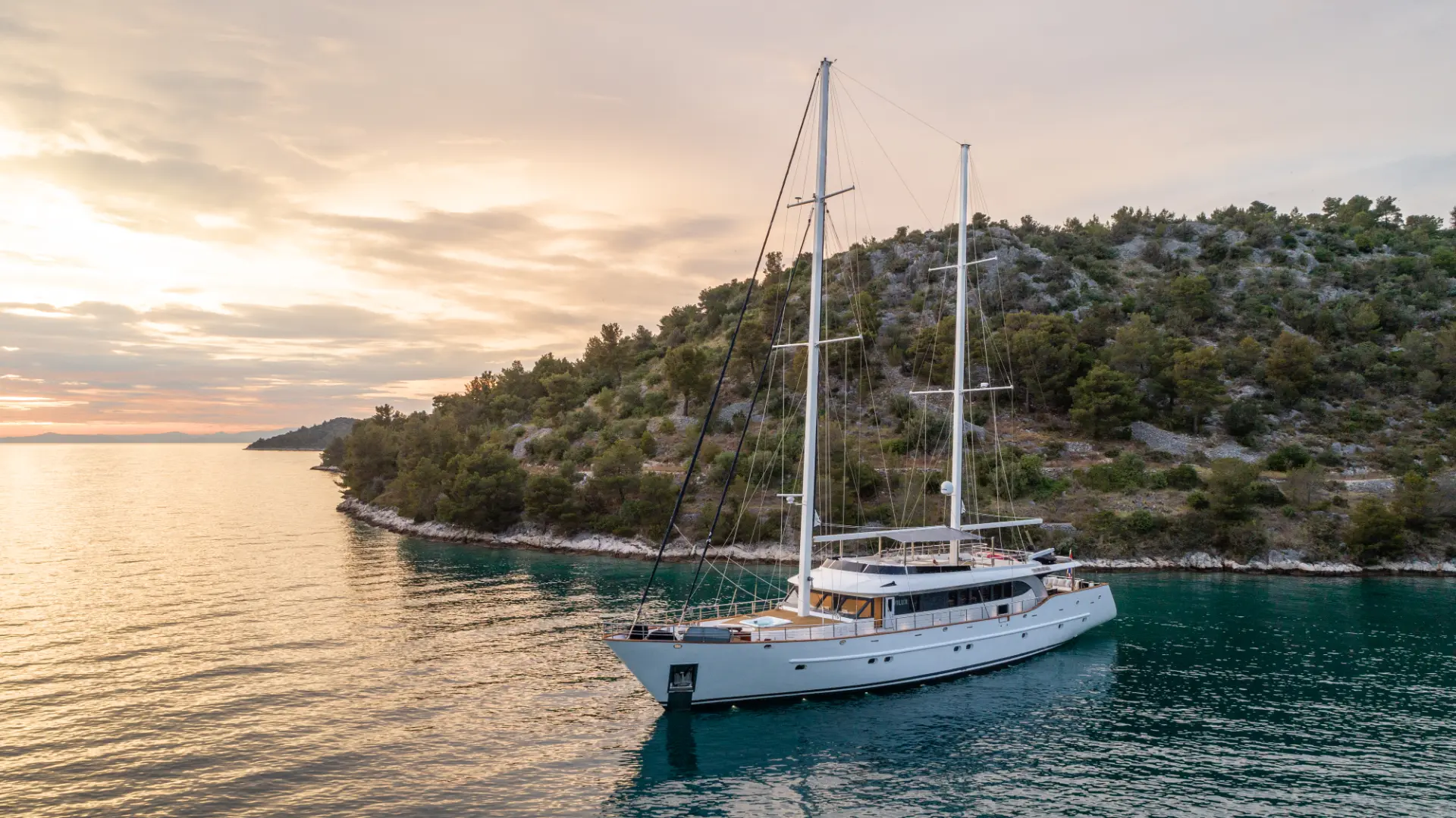 Navilux: anchored at sunset in a peaceful bay, stern ropes tied to the shore.