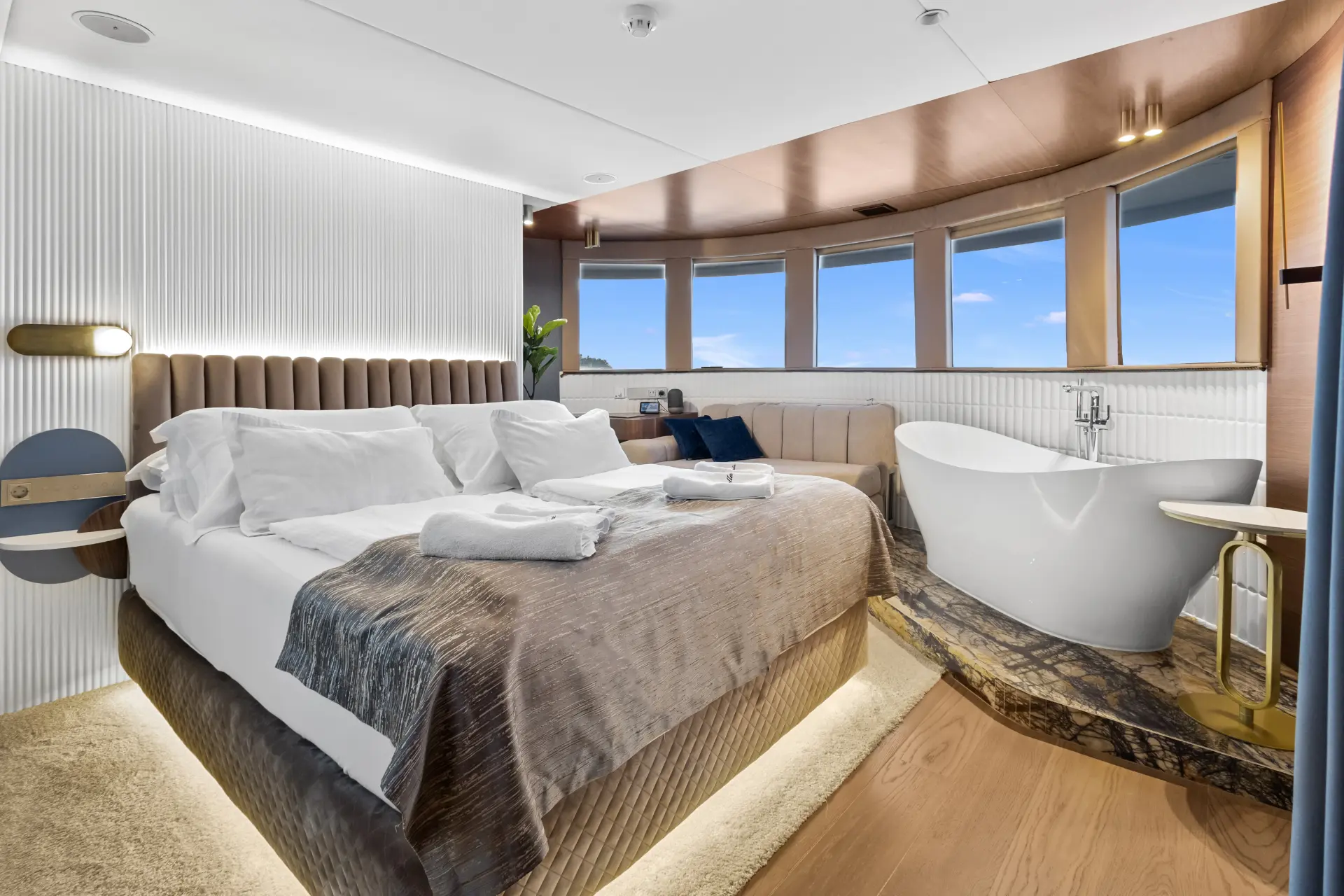 Bella – Elegant double bedroom with bed, large windows, bathtub, and cozy seating area.