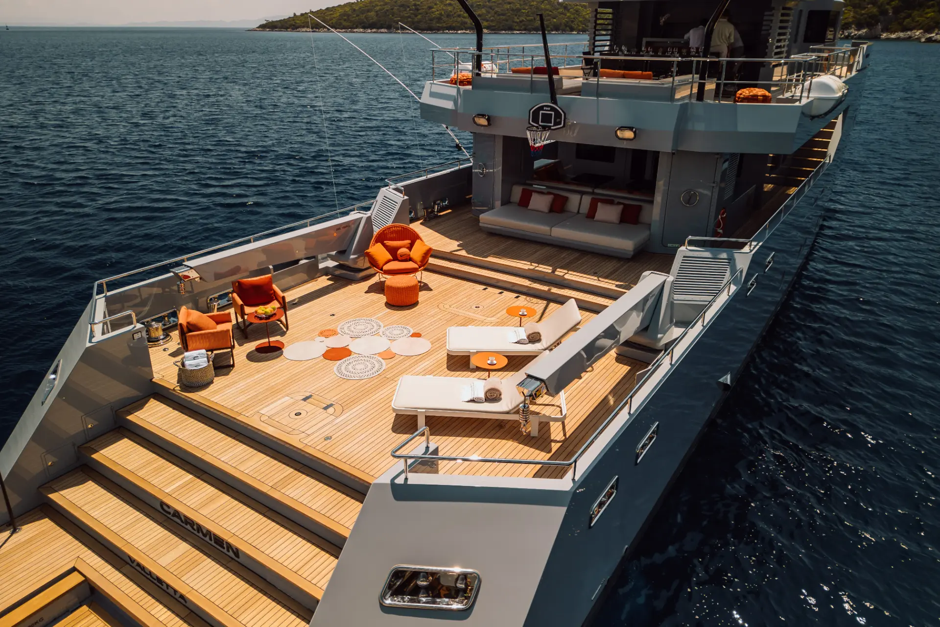 Carmen, detailed aerial of aft teak deck showing sun loungers, seating, tables, and basketball.