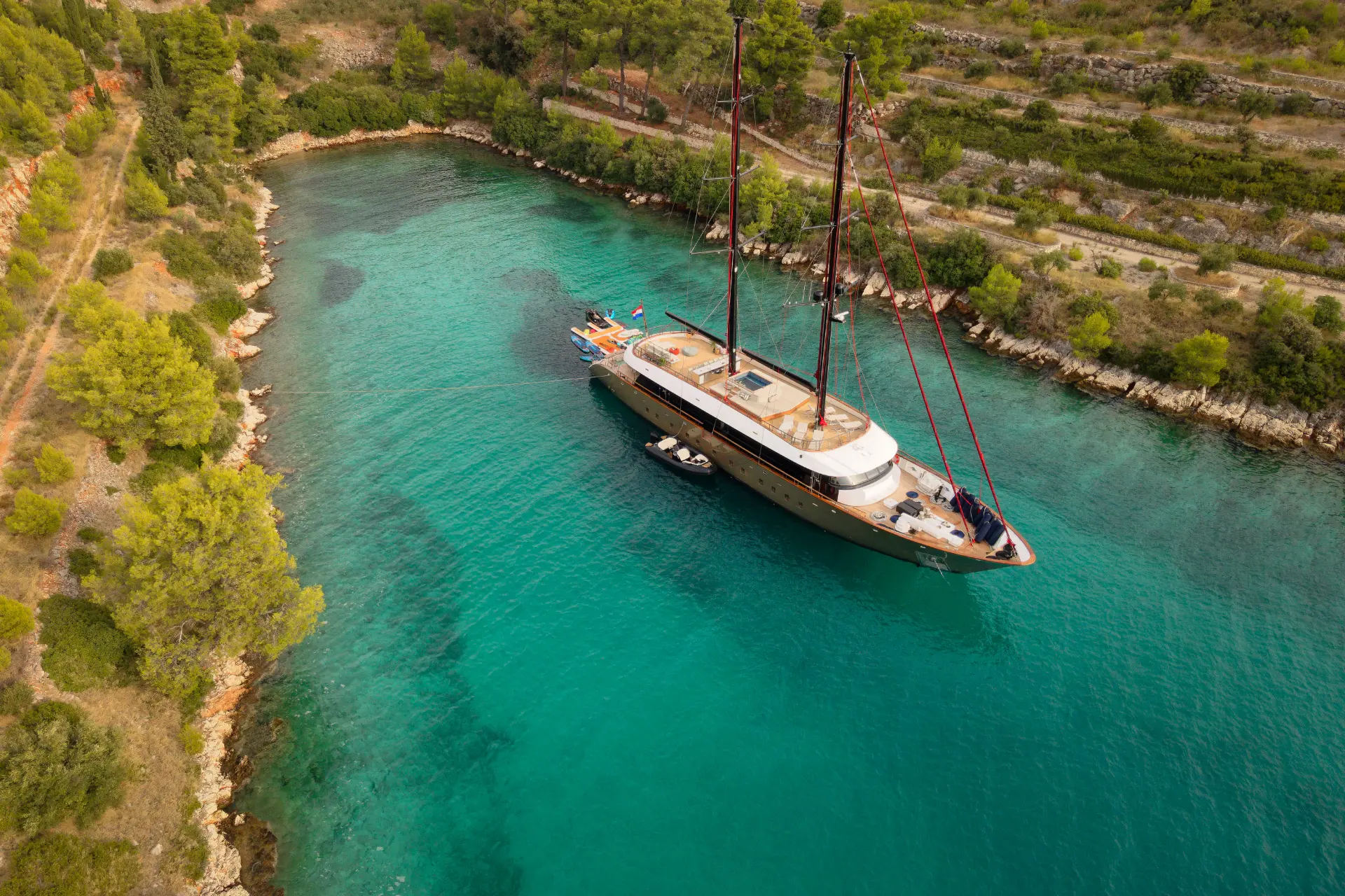 Anetta – aerial image capturing yacht anchored in vibrant turquoise waters near coast.