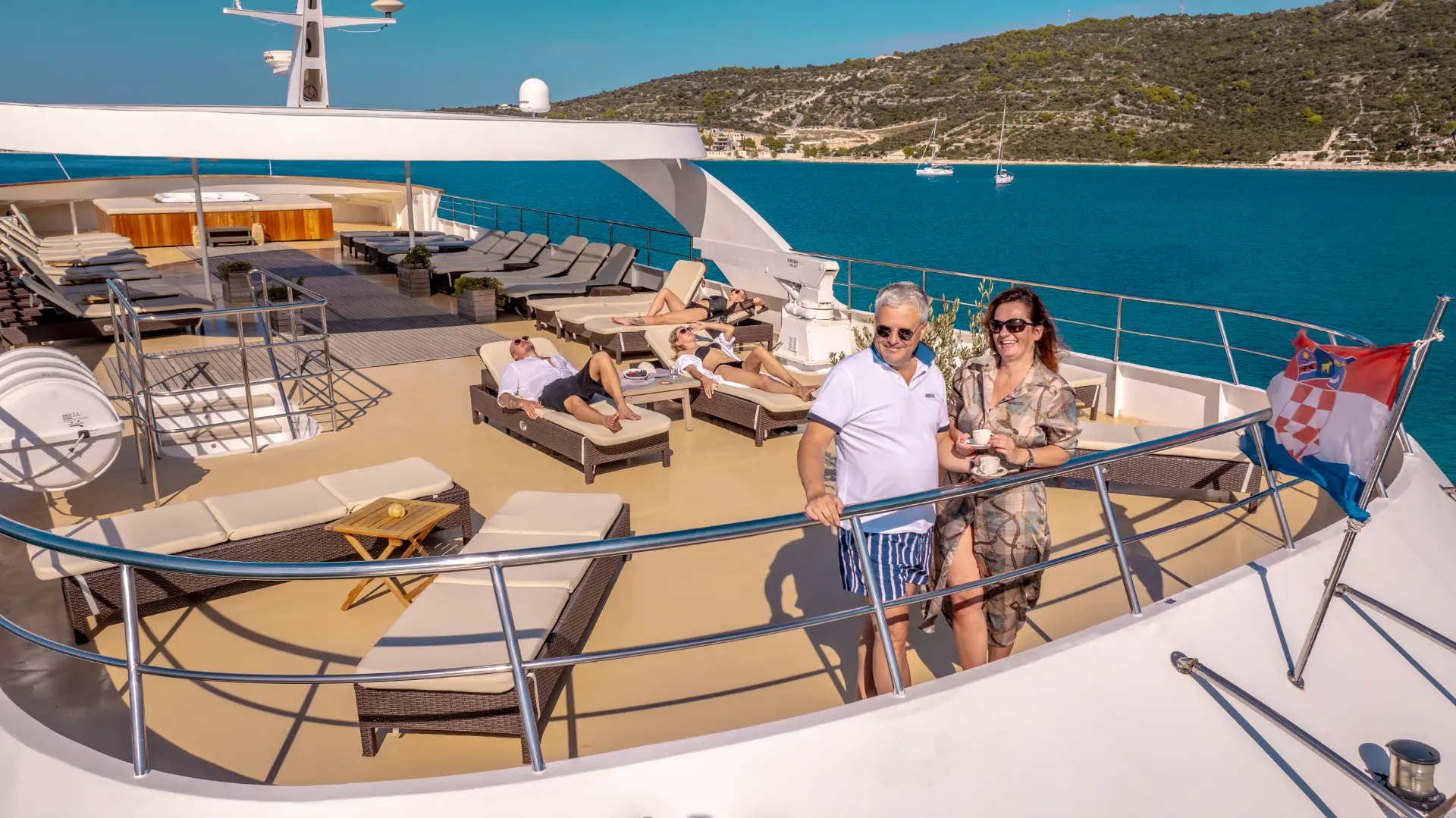 Karizma - guests on aft sundeck, many sun pads, couple relaxing near fence