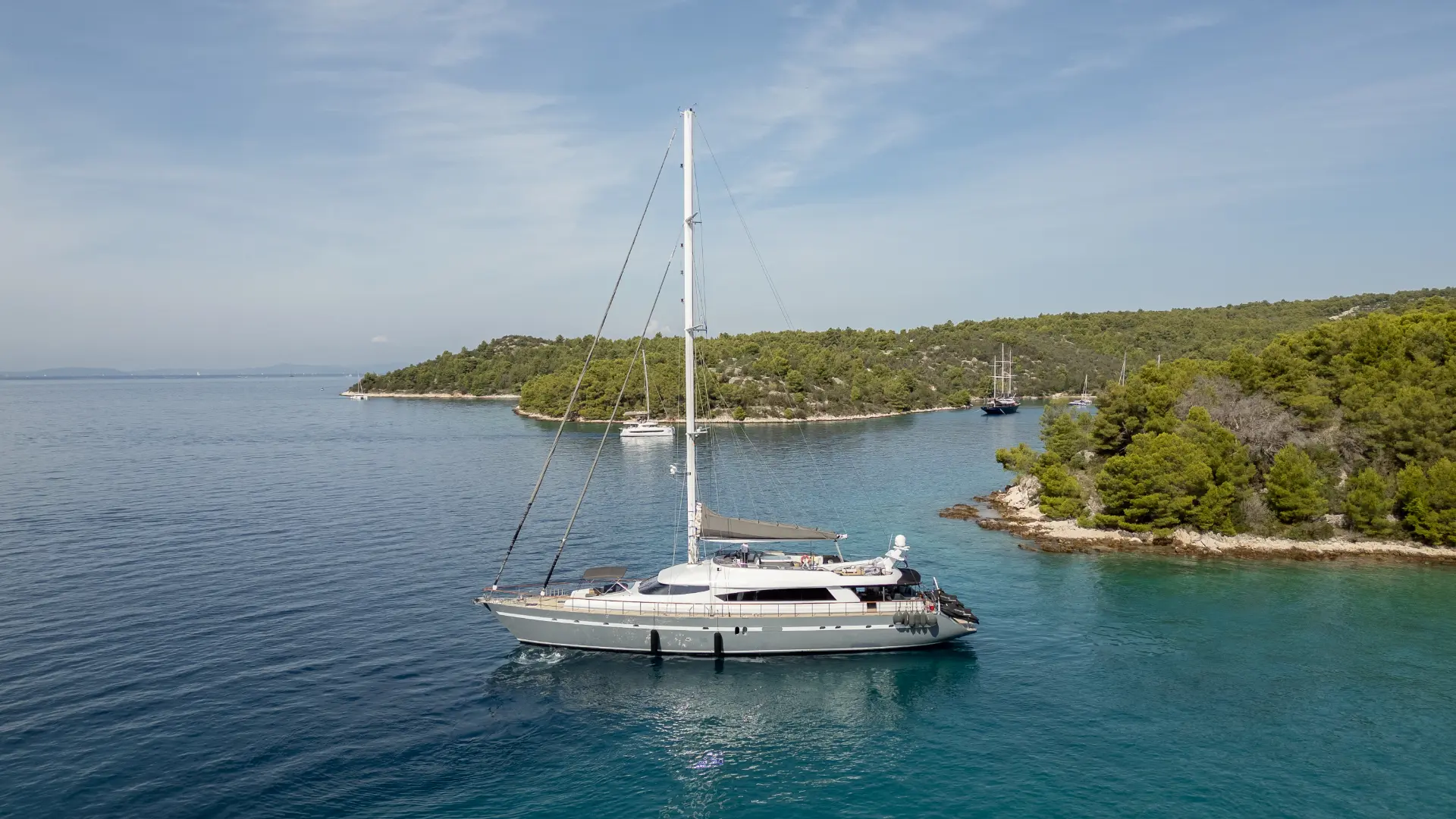 San Limi portside view – yacht anchored near a vibrant green shoreline, surrounded by peaceful blue waters and natural scenery