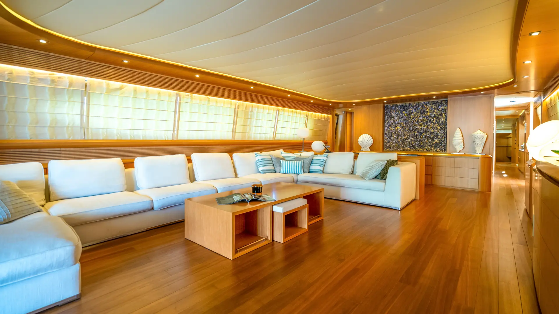 Cynthia – stylish wood and white salon featuring U-shaped sofa, small table, and art on the wall.