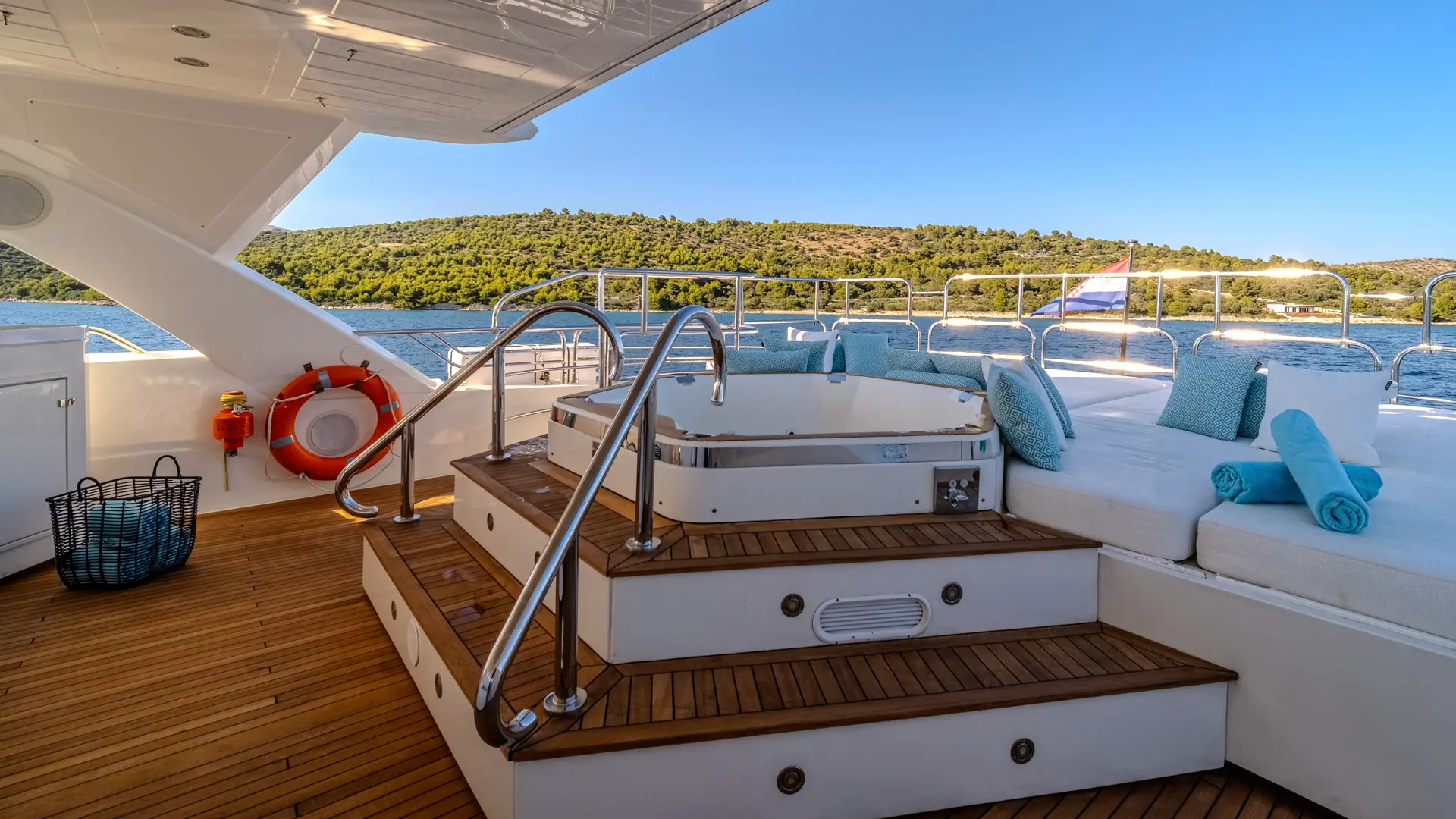 Arago - relaxing jacuzzi near sunbathing area, set against a rich green coastline.