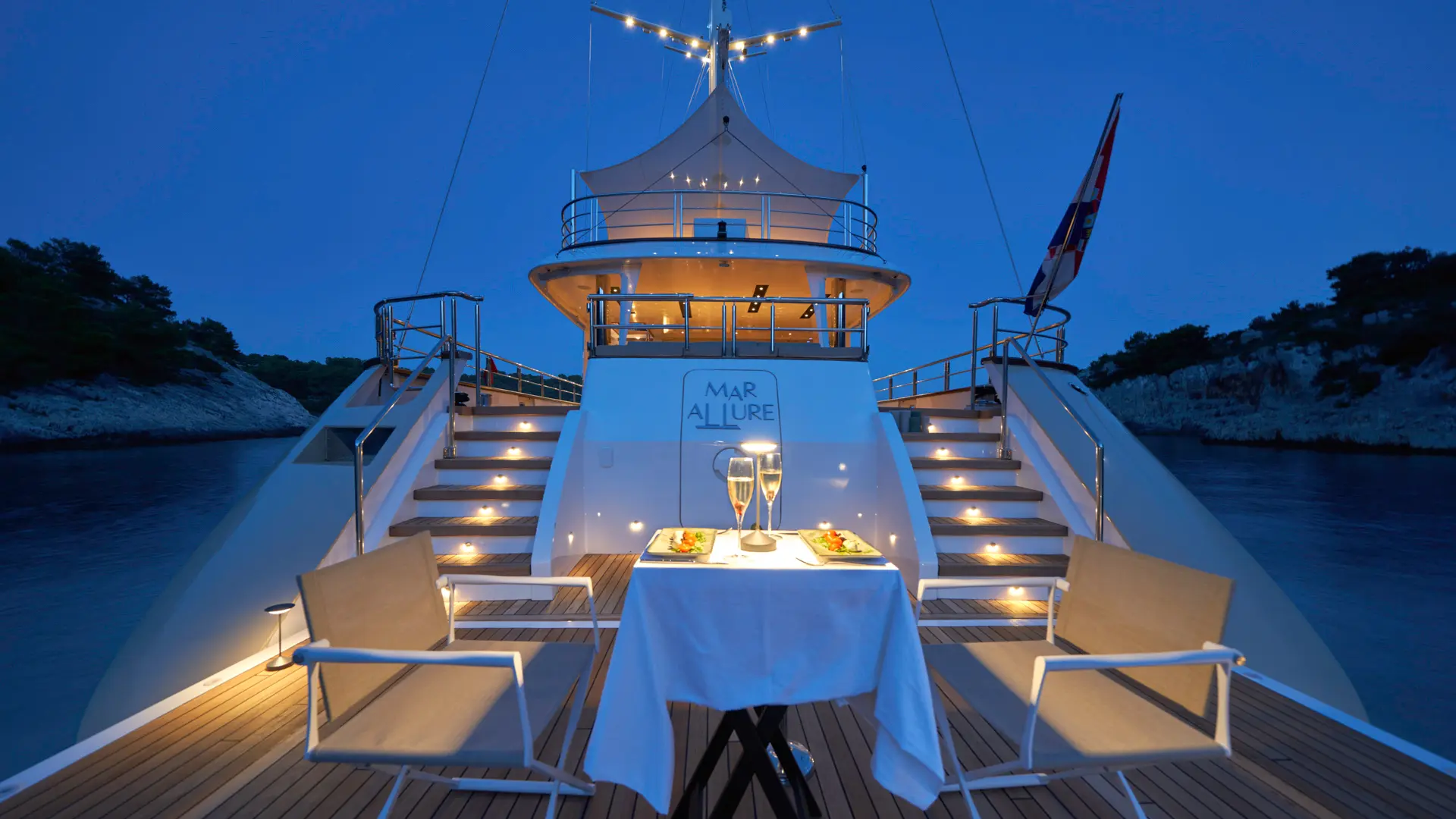 MarAllure – luxury swim platform at sundown with ambient lights on, intimate table set for two.