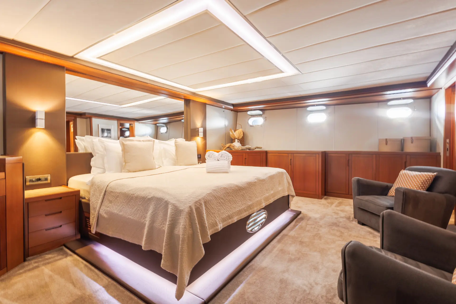 San Limi – master cabin featuring bed, cozy chairs, mirror overhead, and decorative ocean shell art