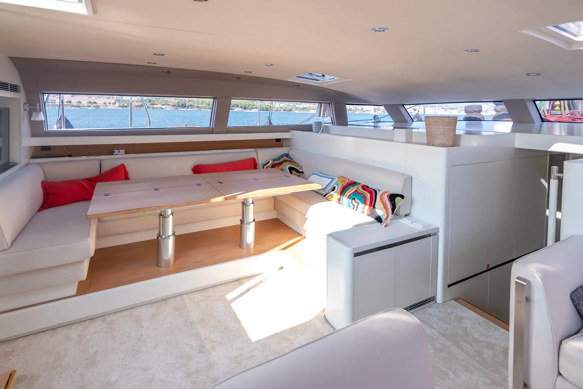 CNB 76 – spacious white salon featuring dining area and cozy seats with vibrant cushions.