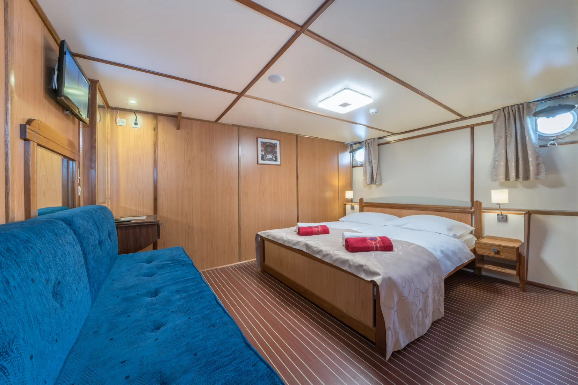 Barbara - elegant ensuite with double bed, blue sofa, and mounted TV.