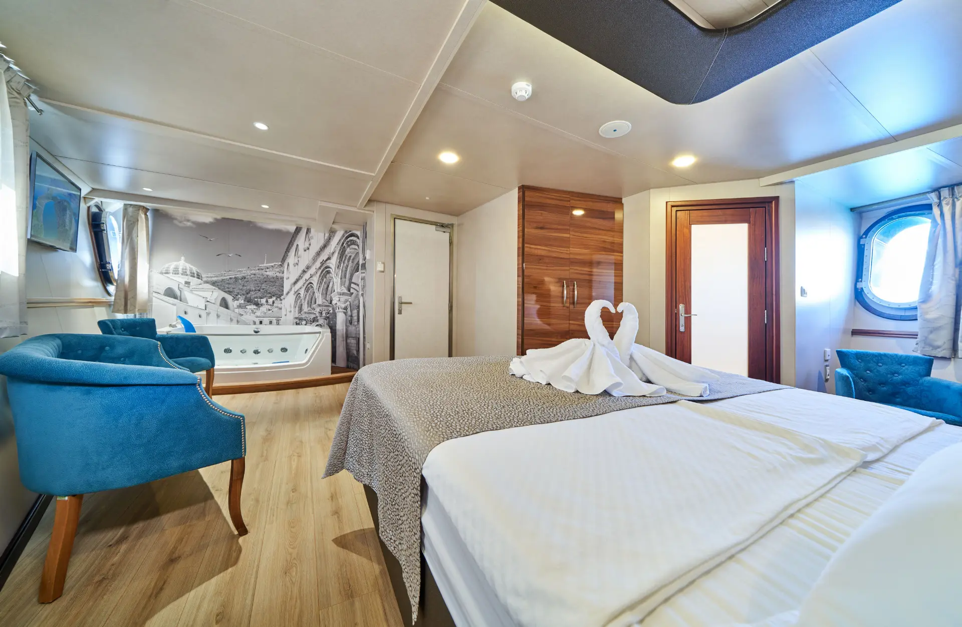 Casablanca – double bedroom with bed, chairs, window, storage, wall photo, and ensuite bath.