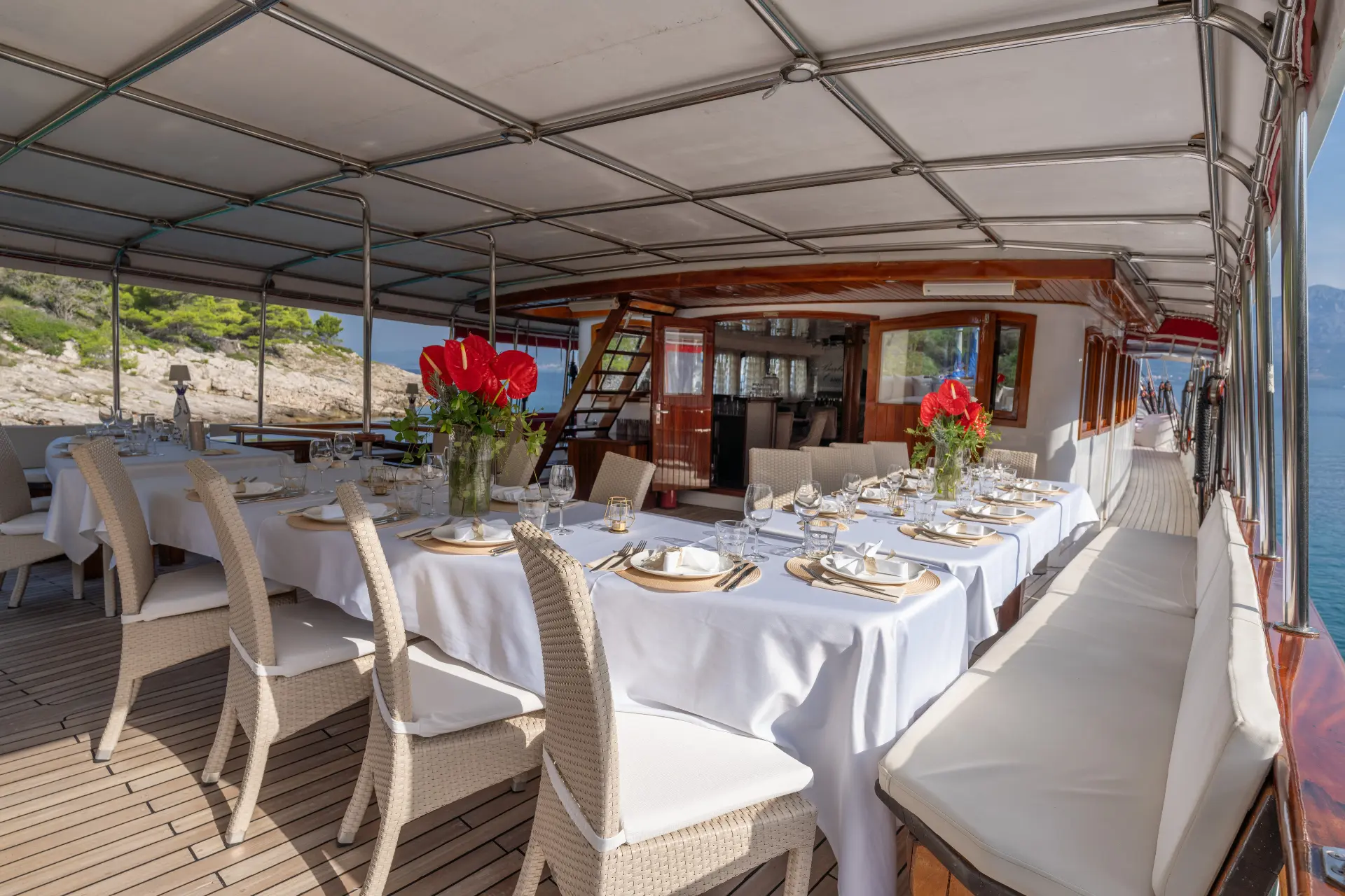 Barbara - covered deck facing bow, entrance in view, dining tables set.