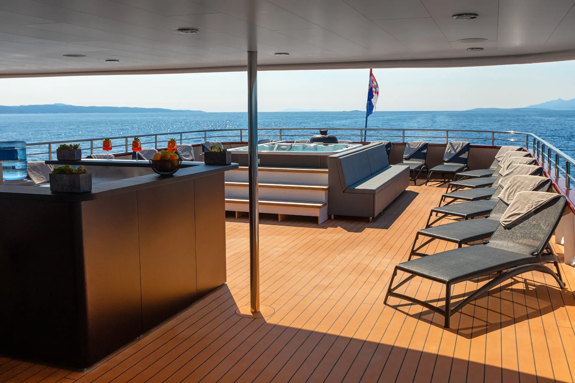 Yolo -view from bar towards the jacuzzi on the sundeck featuring modern deck furniture and a relaxing atmosphere on a luxury cruise.