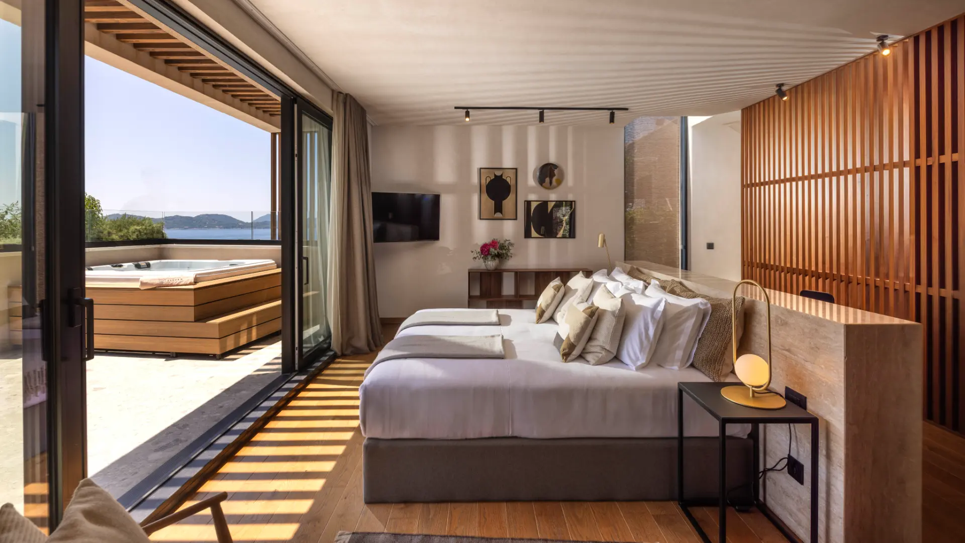 Villa Lumea, upper floor master bedroom featuring double bed, TV, art on walls, floor-to-ceiling glass wall and terrace jacuzzi