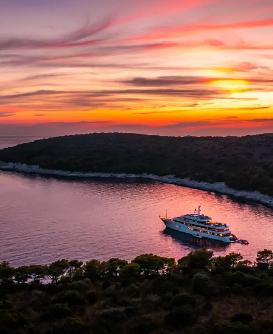 Private Croatia Cruise - Alfa Mario - aerial side view, anchored in bay, water toys floating by swim platform under amazing sky